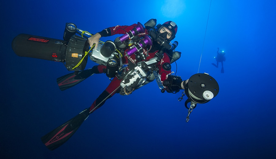 Thibault, sous l'eau, chargé de plusieurs appareil de Laurent Ballesta